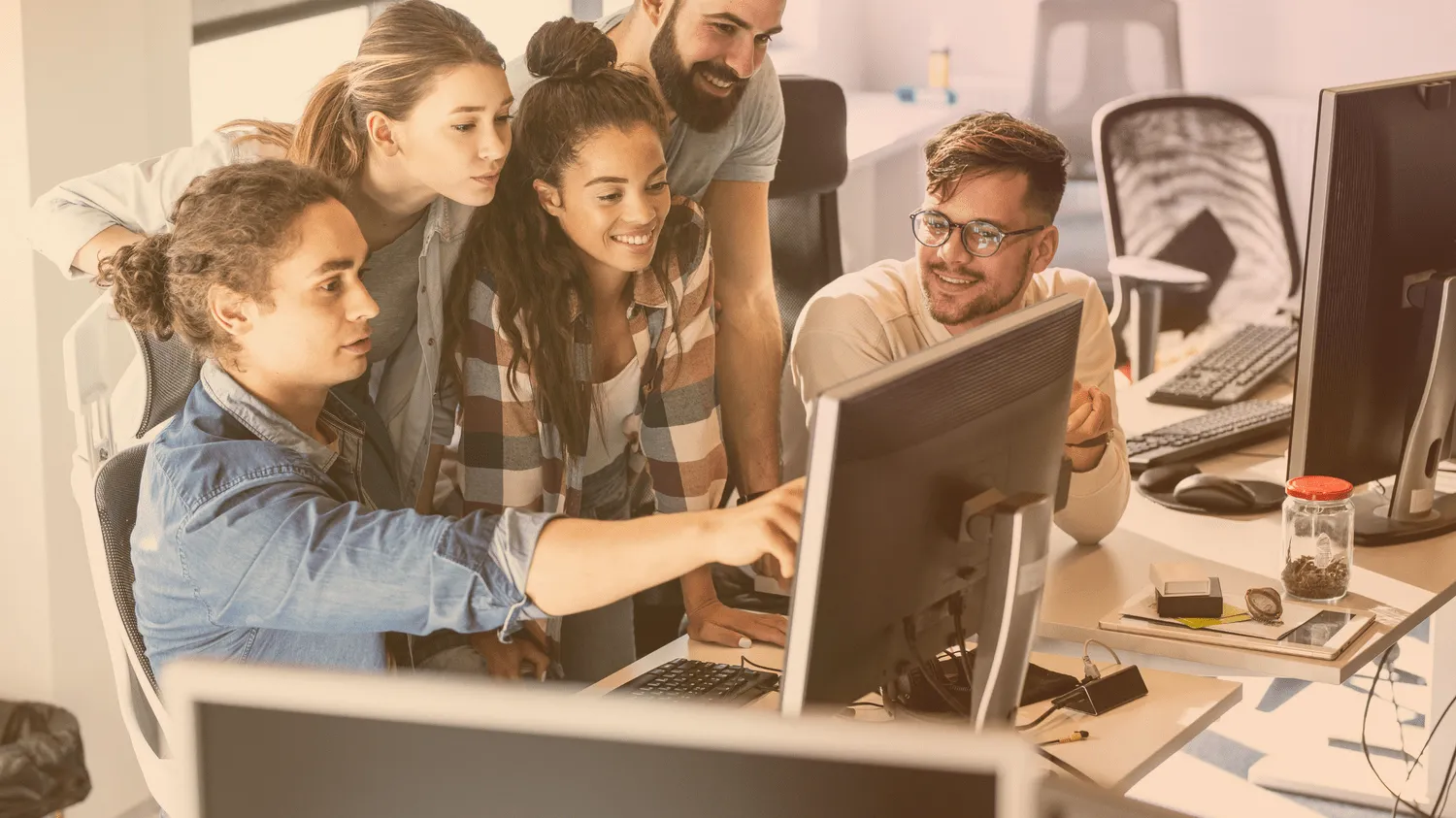 Satisfied web developers behind the monitor while discussing tasks