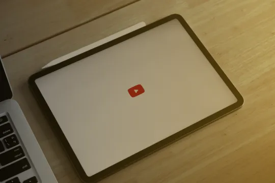 Tablet with YouTube logo on a table close to laptop