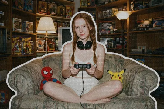 Red-haired girl gamer in a chair with her geeky collection of figures and games behind